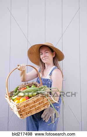 Stock Photo - Mixed race farmer holding basket of vegetables. Fotosearch