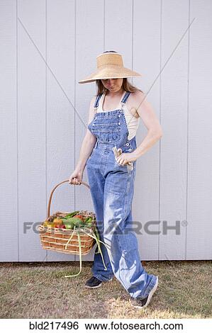 Stock Photograph - Mixed race farmer holding basket of vegetables. Fotosearch