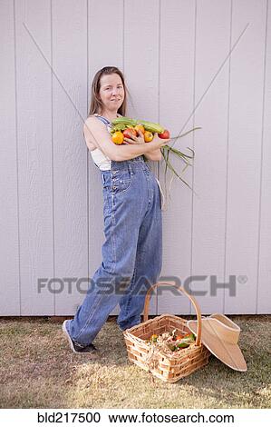 Stock Image - Mixed race farmer with basket of vegetables. Fotosearch