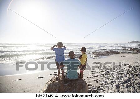 Mixed race father and children sitting on beach View Large Photo Image Picture - Mixed race father and children sitting on beach. Fotosearch