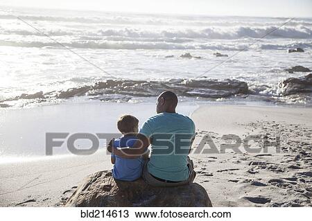 Mixed race father and son sitting on beach View Large Photo Image Stock Image - Mixed race father and son sitting on beach. Fotosearch