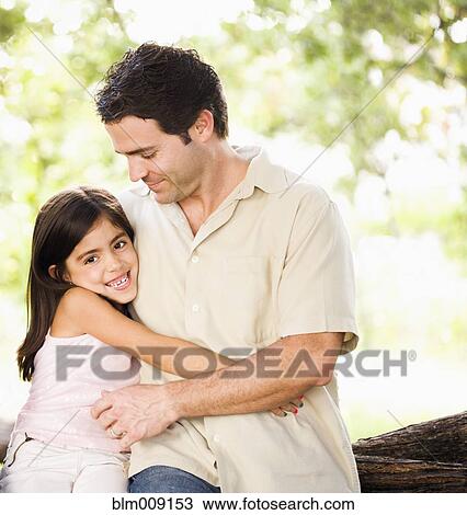 Stock Image - Mixed race father hugging daughter. Fotosearch