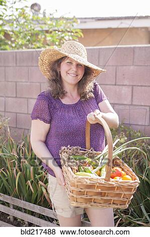 Stock Photo - Mixed race gardener gathering vegetables in garden. Fotosearch