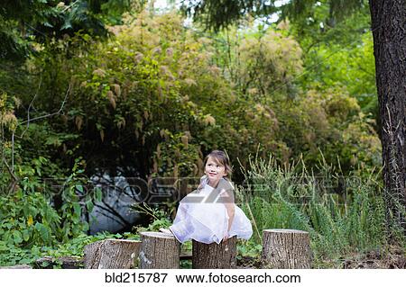 Stock Photo - Mixed race girl balancing on logs in park. Fotosearch