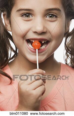 Stock Image - Mixed race girl eating lollipop. Fotosearch