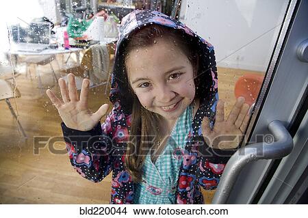 Picture - Mixed race girl looking out rainy window. Fotosearch