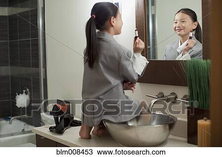 Mixed race girl on counter putting on lipstick View Large Photo Image Stock Image - Mixed race girl on counter putting on lipstick. Fotosearch