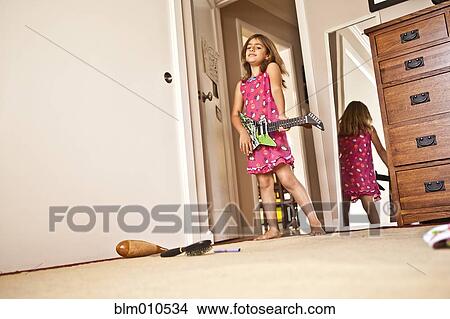 Picture - Mixed race girl playing guitar in bedroom. Fotosearch