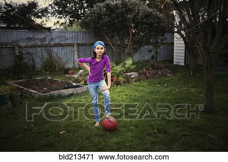 Mixed Race Girl Playing With Soccer Ball In Backyard Stock Image