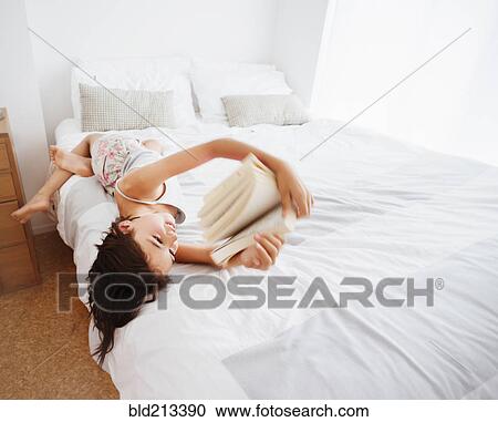 Mixed race girl reading book on bed View Large Photo Image Stock Image - Mixed race girl reading book on bed. Fotosearch