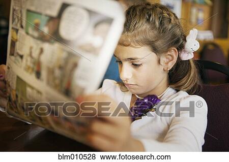 Stock Photo - Mixed race girl reading newspaper. Fotosearch
