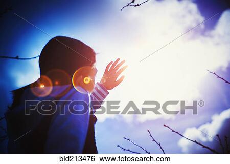 Stock Photograph - Mixed race girl shielding herself from sun lens flare. Fotosearch