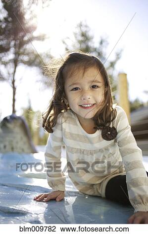 Stock Image - Mixed race girl sitting outdoors. Fotosearch