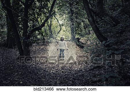 Stock Photograph - Mixed race girl standing in beam of light in forest. Fotosearch