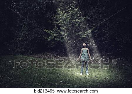 Stock Photography - Mixed race girl standing in beam of light outdoors. Fotosearch