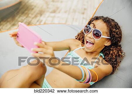 Mixed race girl taking selfie with cell phone on patio View Large Photo Image Stock Image - Mixed race girl taking selfie with cell phone on patio. Fotosearch