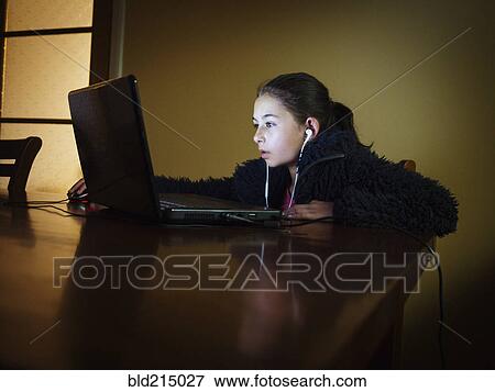 Mixed race girl using laptop at table night View Large Photo Image Stock Photo - Mixed race girl using laptop at table night. Fotosearch