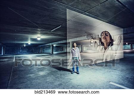 Stock Photo - Mixed race girl watching holographic screen in parking lot. Fotosearch