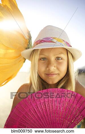 Stock Image - Mixed race girl with large flower and fan. Fotosearch