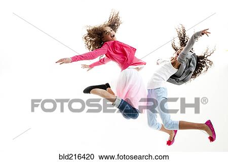 Stock Image - Mixed race girls jumping for joy. Fotosearch