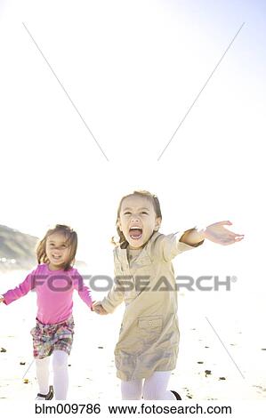 Stock Photograph - Mixed race girls running on beach. Fotosearch