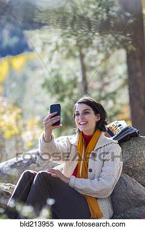 Stock Photography - Mixed race hiker taking cell phone selfie in forest. Fotosearch