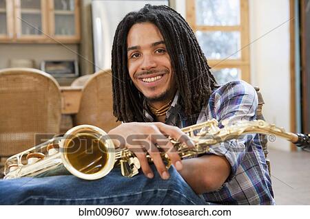 Stock Photo - Mixed race man holding saxophone. Fotosearch