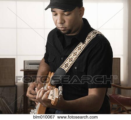 Stock Photo - Mixed race man playing electric guitar. Fotosearch