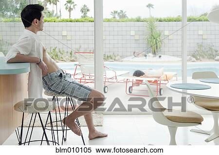 Stock Photography - Mixed race man sitting on bar stool. Fotosearch