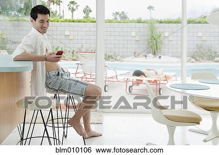 Stock Photograph - Mixed race man text messaging on cell phone. Fotosearch