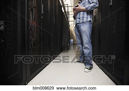 Stock Photo - Mixed race man working in office technology room. Fotosearch