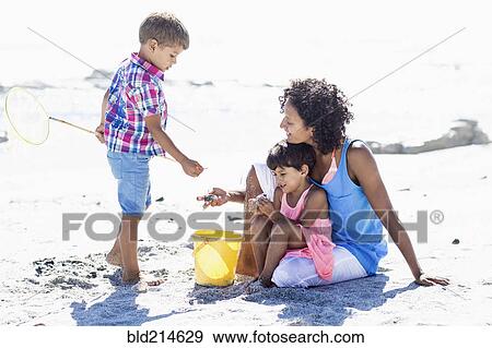 Stock Photo - Mixed race mother and children playing on beach. Fotosearch