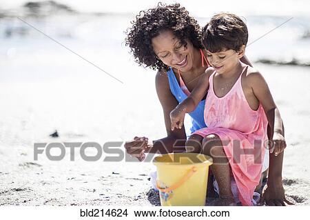 Picture - Mixed race mother and daughter playing on beach. Fotosearch