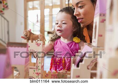 Picture - Mixed race mother and daughter playing with dollhouse. Fotosearch