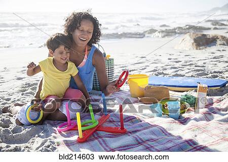 Stock Image - Mixed race mother and daughter playing at beach. Fotosearch