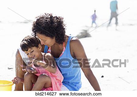 Stock Photo - Mixed race mother and daughter playing on beach. Fotosearch