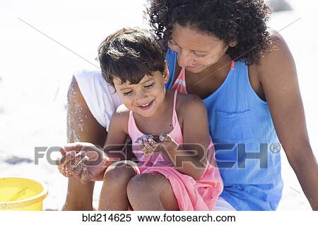Stock Photography - Mixed race mother and daughter playing on beach. Fotosearch