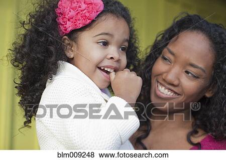 Stock Photo - Mixed race mother and daughter smiling. Fotosearch