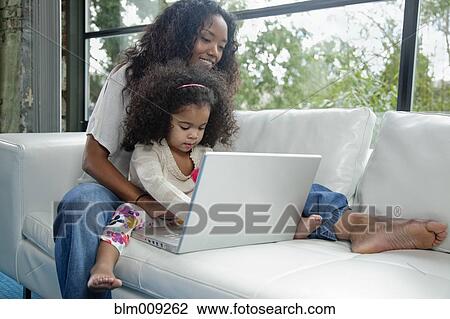 Mixed race mother and daughter using laptop on sofa View Large Photo Image Stock Image - Mixed race mother and daughter using laptop on sofa. Fotosearch
