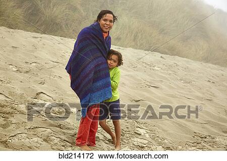 Stock Image - Mixed race mother and son hugging on beach. Fotosearch