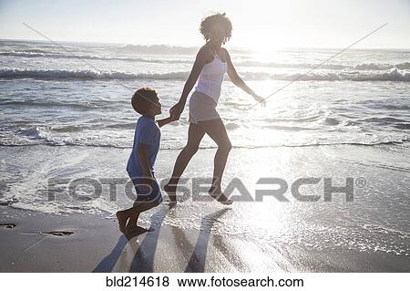 Mixed race mother and son playing in ocean waves on beach View Large Photo Image Stock Photo - Mixed race mother and son playing in ocean waves on beach. Fotosearch