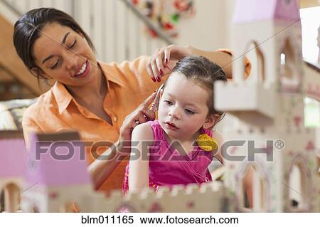 Stock Photography - Mixed race mother brushing daughter's hair. Fotosearch