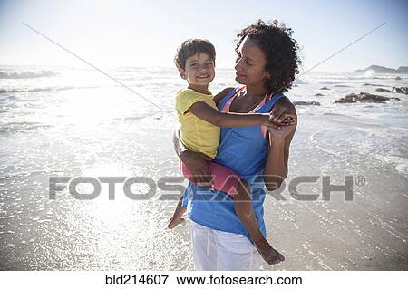 Mixed race mother carrying daughter on beach View Large Photo Image Stock Photo - Mixed race mother carrying daughter on beach. Fotosearch