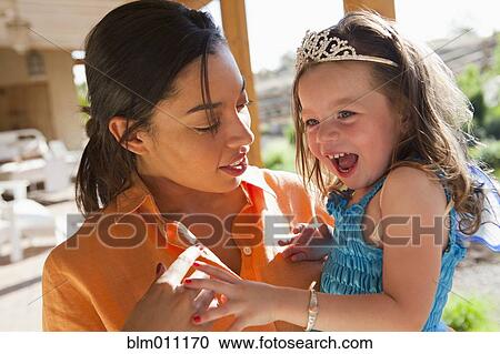 Stock Image - Mixed race mother holding princess daughter. Fotosearch