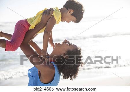 Mixed race mother lifting daughter at beach View Large Photo Image Stock Photography - Mixed race mother lifting daughter at beach. Fotosearch