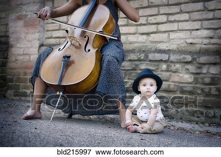 Stock Photo - Mixed race musician playing cello with baby daughter. Fotosearch