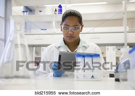 Stock Photography - Mixed race scientist using digital tablet in laboratory. Fotosearch