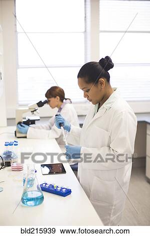 Stock Photo - Mixed race scientists working in laboratory. Fotosearch