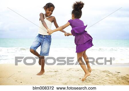 Mixed race sisters holding hands playing on beach View Large Photo Image Stock Image - Mixed race sisters holding hands playing on beach. Fotosearch