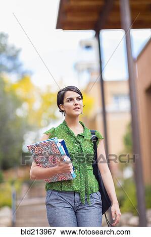 Stock Photo - Mixed race student carrying books on campus. Fotosearch
